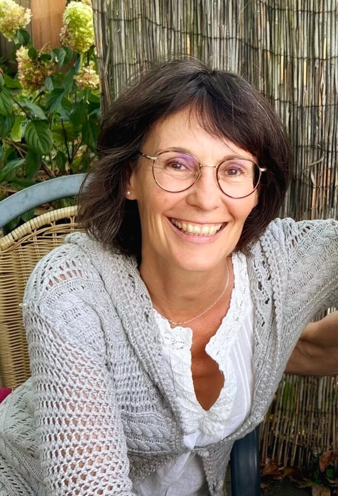 Daniele Weiler, lächelnd in einem Korbstuhl im Garten